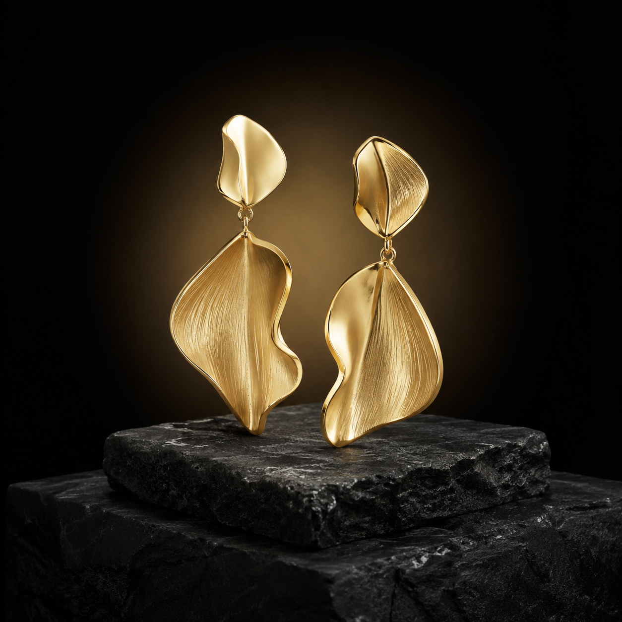 Brincos de ouro em forma de folha sobre pedestal de pedra escura
