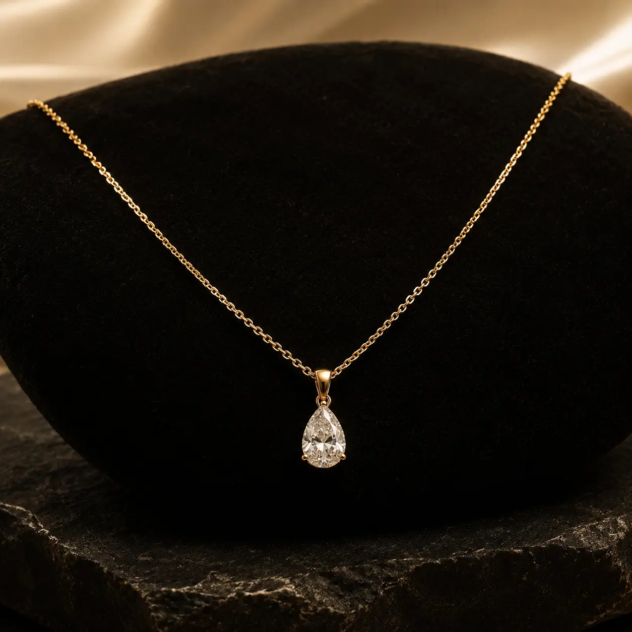 Gargantilha de ouro com pingente em gota apoiada sobre pedra escura