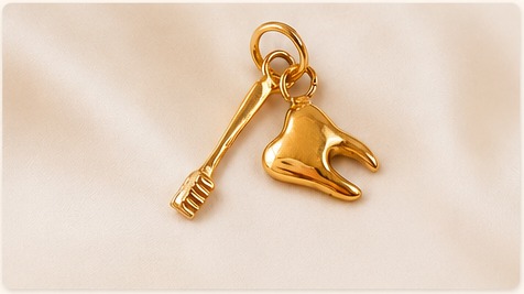 Pingentes de ouro em formato de dente e instrumento odontológico