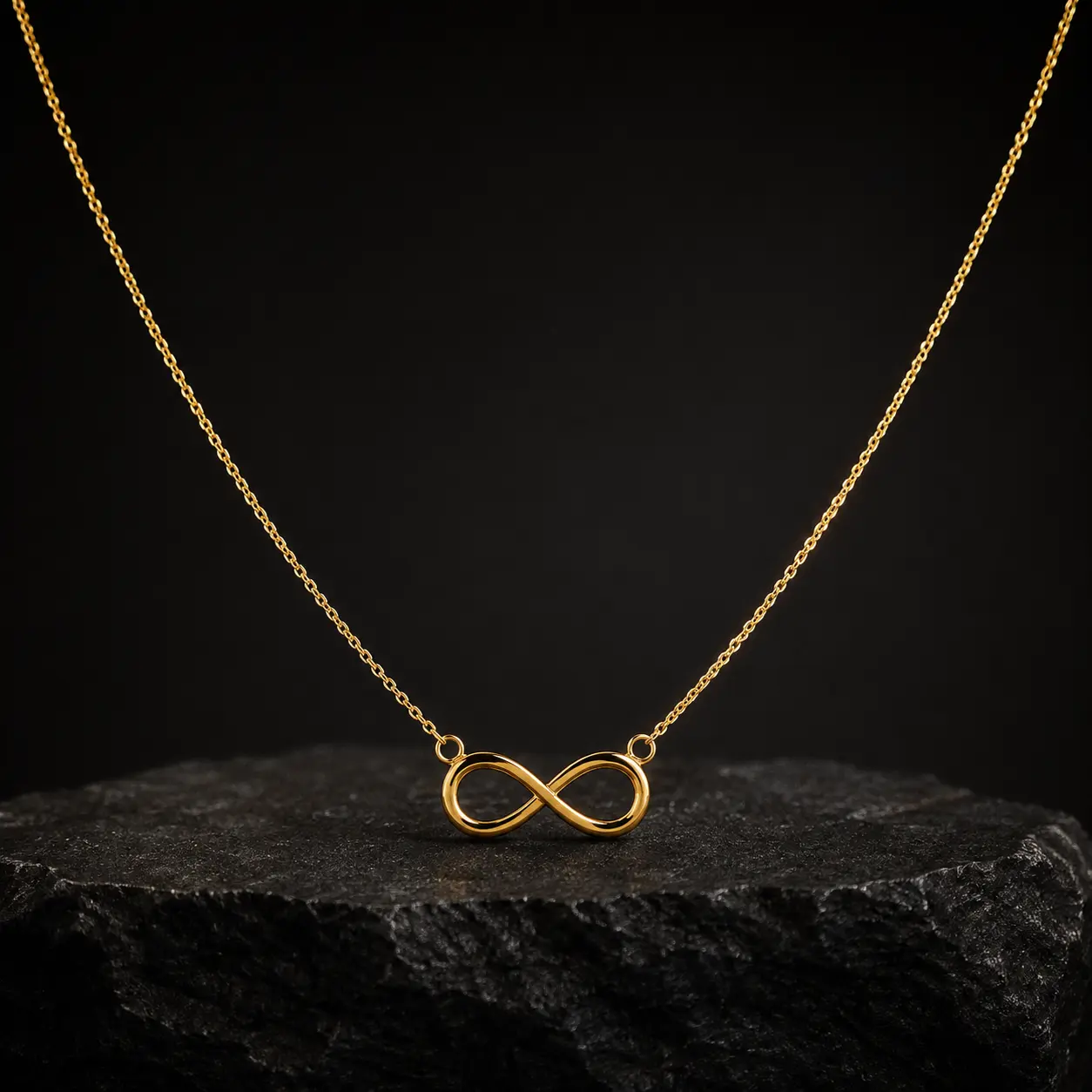 Colar de ouro com pingente símbolo do infinito sobre pedra escura